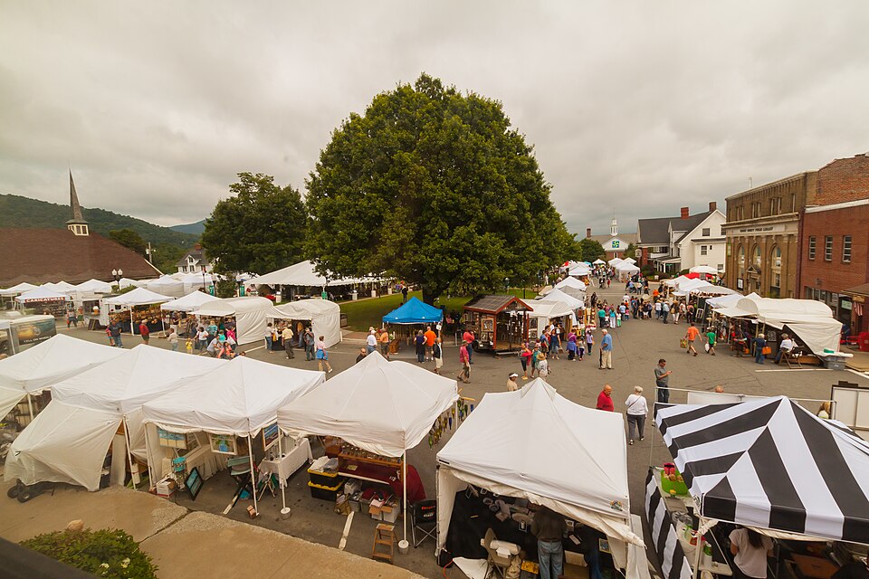 A large craft fair, with tents and stalls, in an American town full of brick buildings and a church