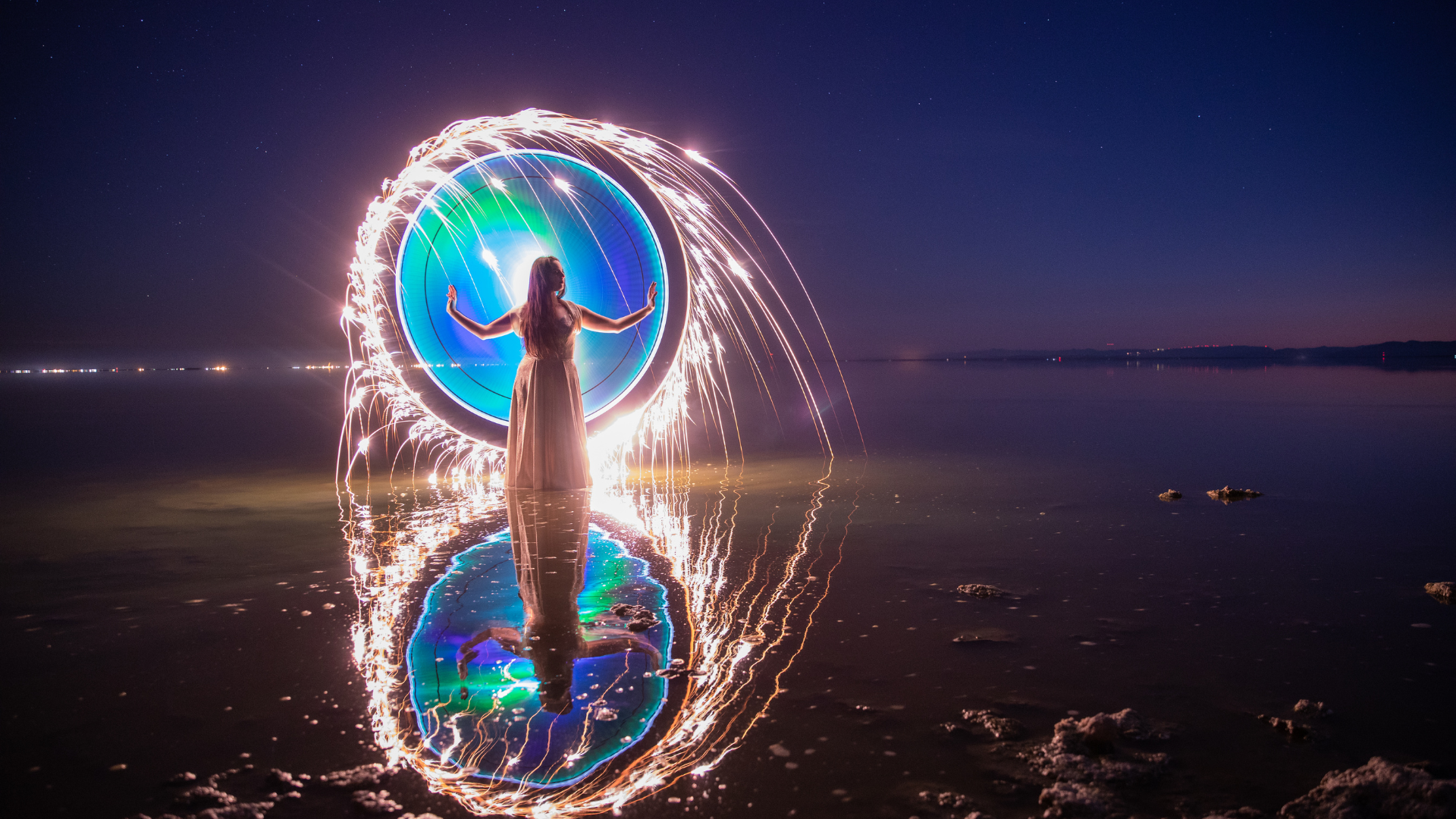 A woman on a seashore with the tide out, conjuring a glowing bubble of magic ringed in sparks