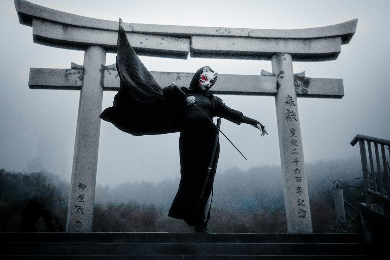 A person in traditional Japanese Kitsune costume, preparing to defend a torii (shrine) with their katana