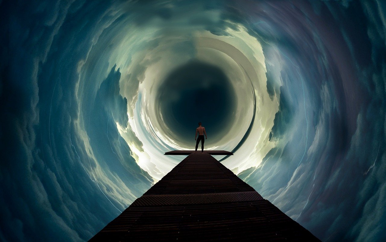 A man standing on the end of a dock in a dark portal