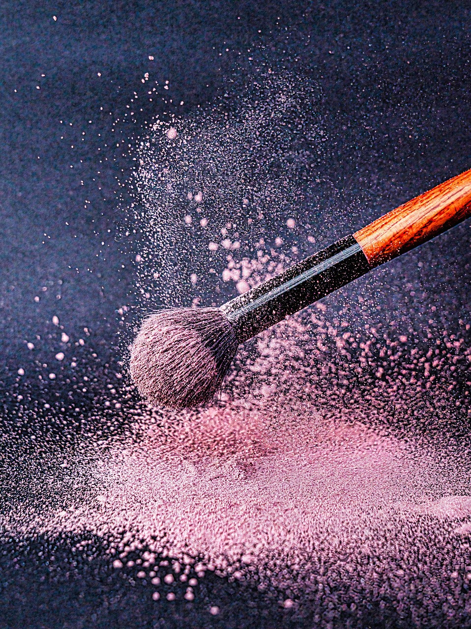 A closeup of blush powder and a makeup brush scattering it