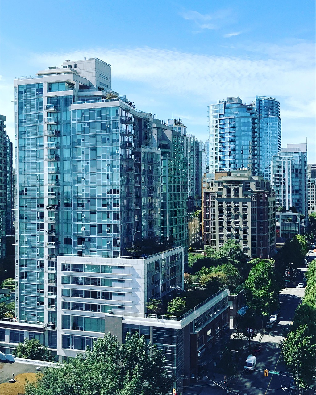A view of buildings in downtown Vancouver, on a sunny day, displaying rooftop gardens and city greenery